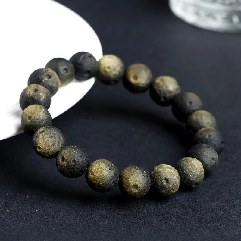 Natural obsidian crater ball bracelet with hand-ground texture, showing silver stone meteorite colour variation
