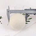Set of 100% wool anti-static drying balls next to a plain cotton storage bag on a laundry background.