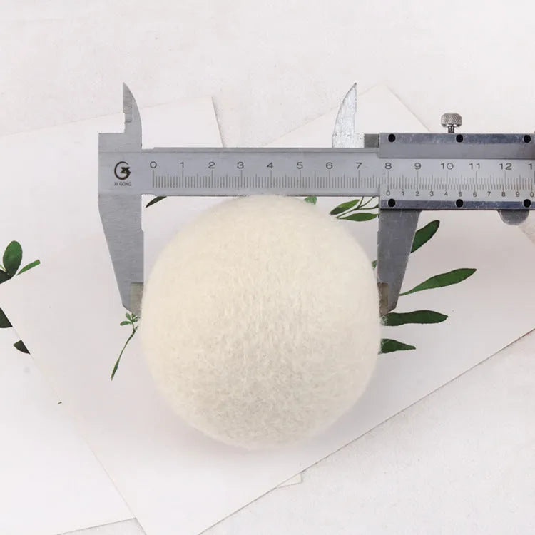 Set of 100% wool anti-static drying balls next to a plain cotton storage bag on a laundry background.