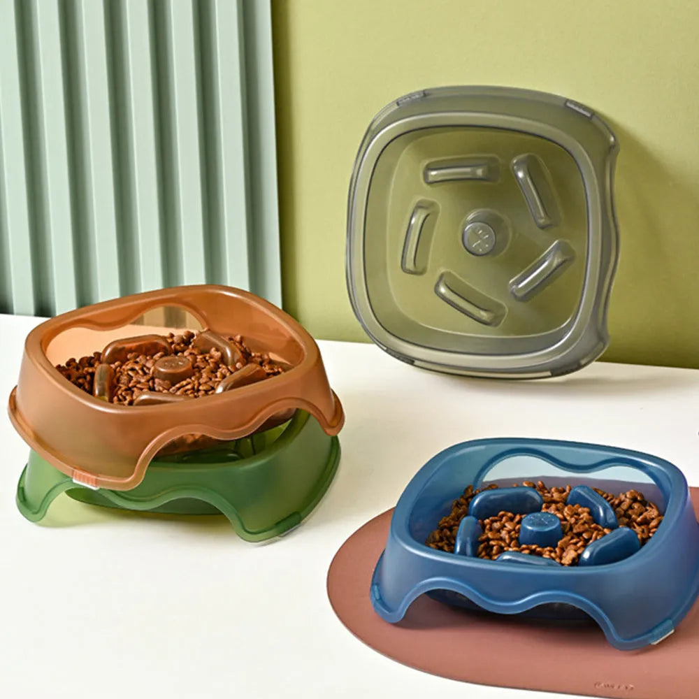 A blue plastic dog slow feeder bowl designed to prevent choking, shown alongside grey, green, and orange colour options.