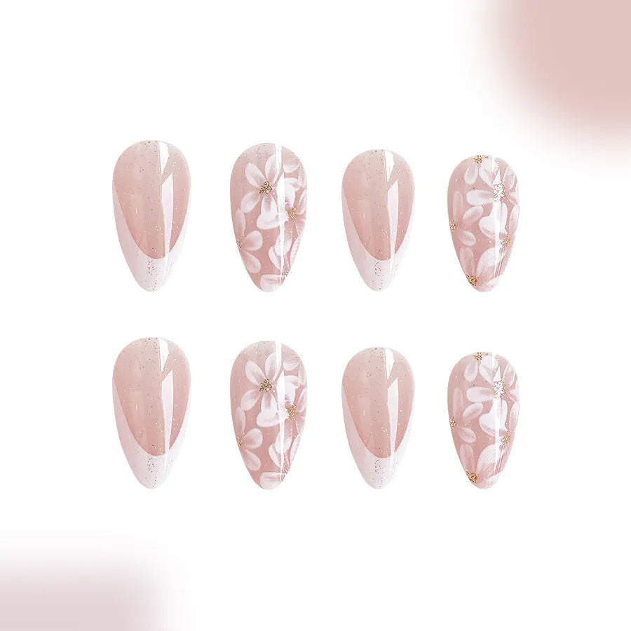 Short almond-shaped artificial nails with white French tips and glittering powder flower designs on translucent base