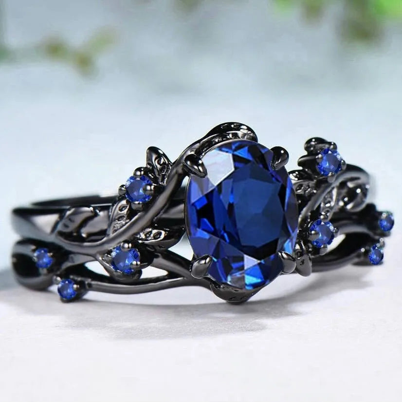Gun black and navy blue rhinestone geometric couple ring for women on a plain background.