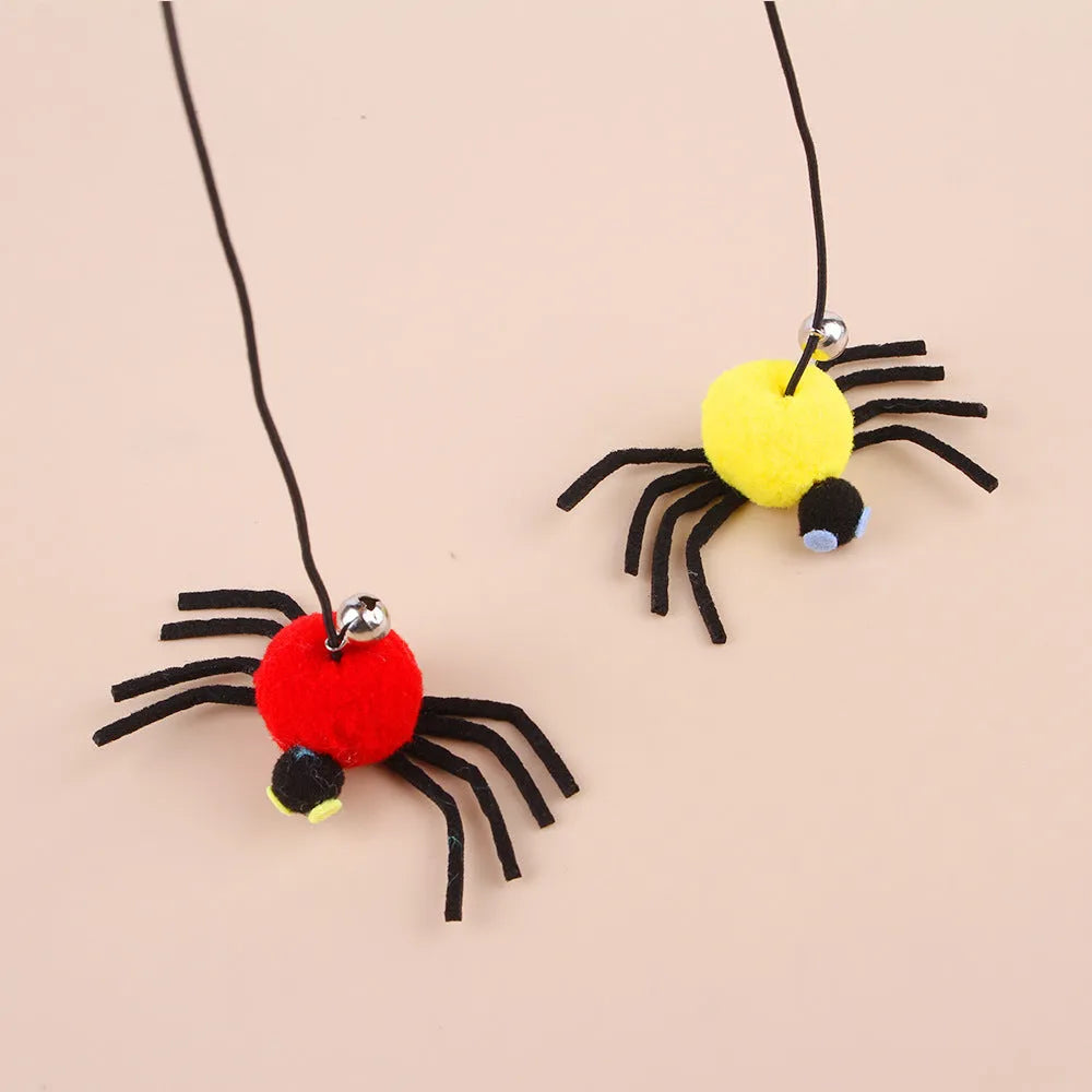 Red and yellow elastic rope cat toy hanging from a door, with feathers, a plastic spider, and a bell.