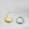 Titanium alloy concave-convex carved nose ring in gold and silver colours on a plain background.