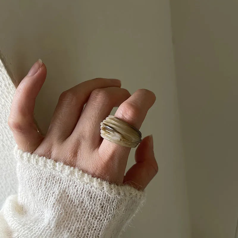 Geometric irregular resin wide ring in brown and white colour options on a hand.