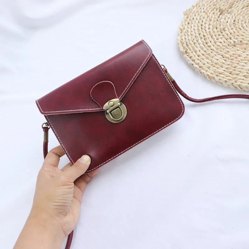 Retro soft-surface crossbody messenger bag with flap closure and lock detail in wine red colour