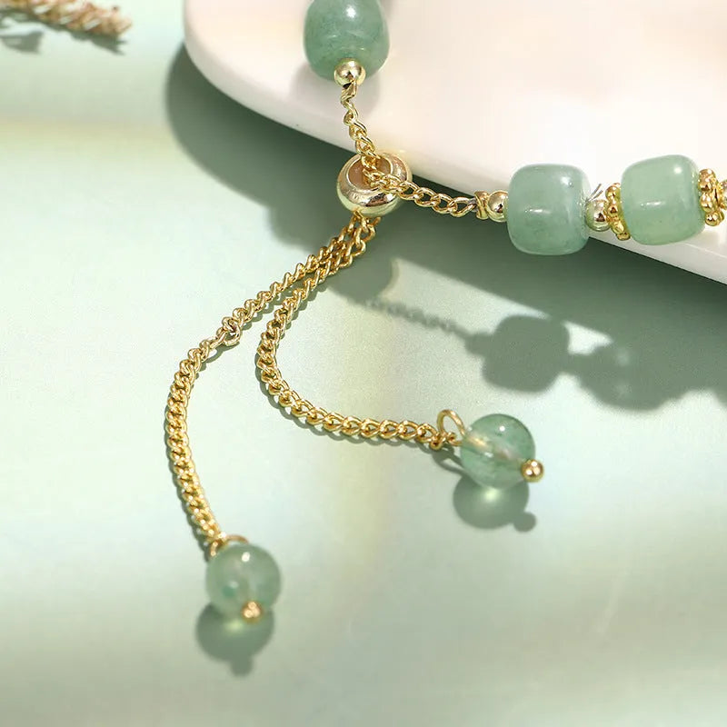 Women's rabbit charm bracelet with green aventurine and strawberry quartz beads, copper and gold details.