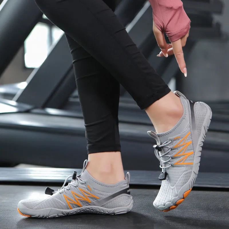 Low-top black and grey indoor training sneakers with mesh upper and rubber sole on a gym floor.