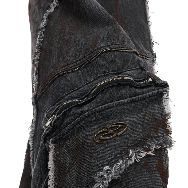 Black gradient denim coat with distressed raw edges and padded shoulders, worn with matching black denim trousers.