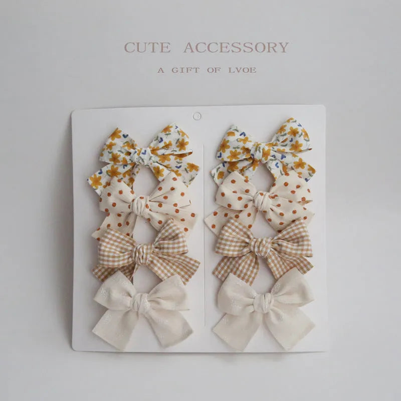 Children's dovetail bow hairclips in cloth, showing colour options like beige brown grid dots and blue flowers.