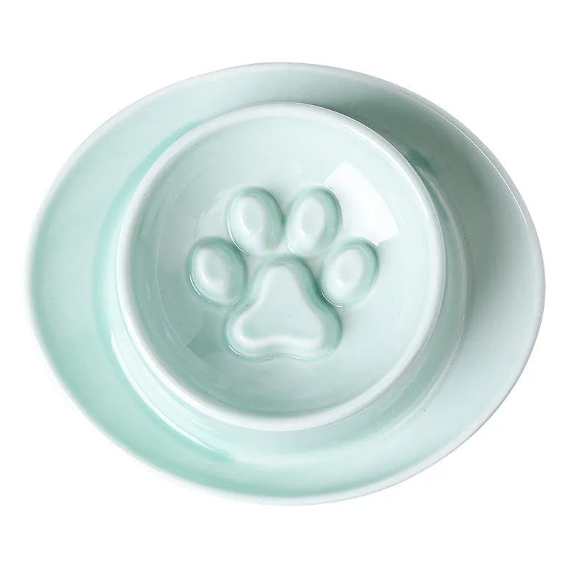 Green ceramic slow feeder pet bowl with maze pattern and non-slip silicone base on a kitchen floor.