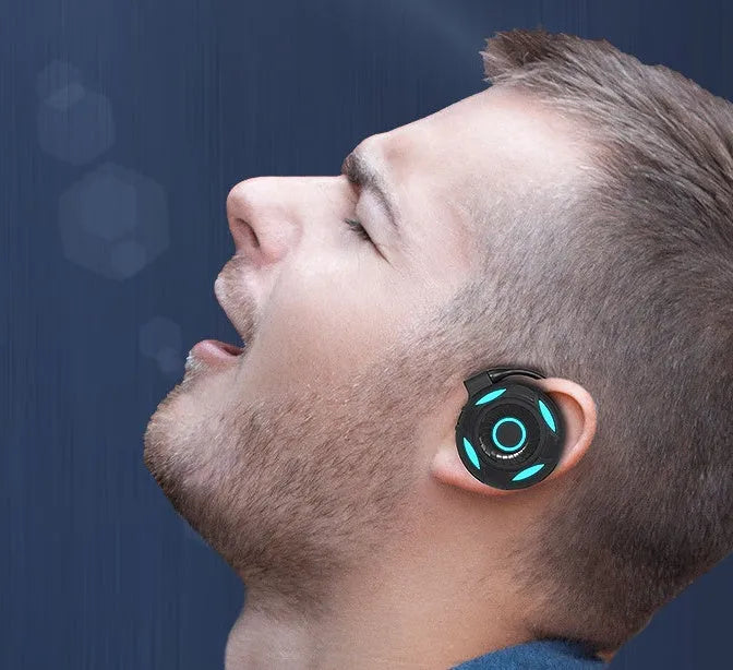 Black and white Bluetooth wireless earphones with hanging ear design showing USB connection option