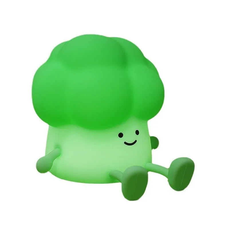Cartoon-shaped eggplant night lamp glowing with soft yellow light on a table.