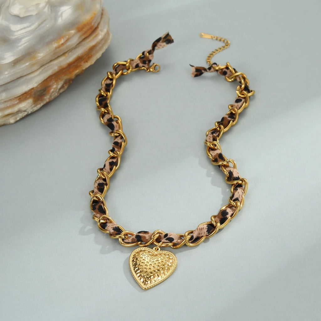 Close-up of a stainless steel necklace with a geometric leopard love pendant on an adjustable 18K-plated chain.
