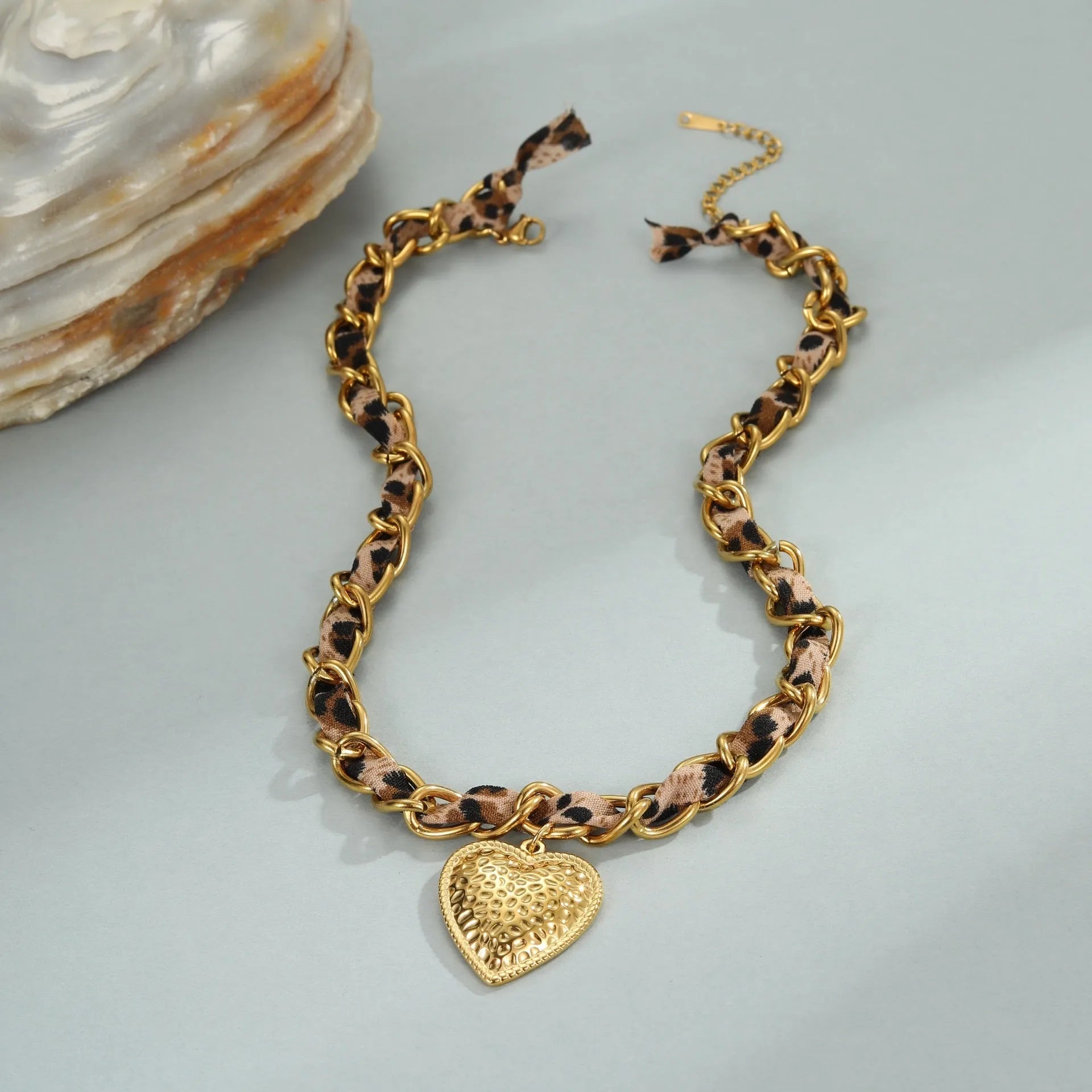 Close-up of a stainless steel necklace with a geometric leopard love pendant on an adjustable 18K-plated chain.