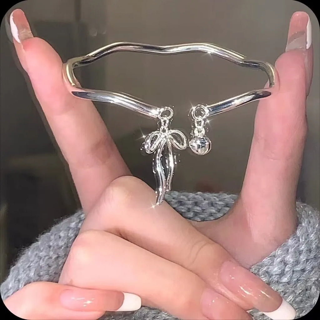 Silver adjustable bow bracelet with zinc alloy construction and electroplated finish on wrist
