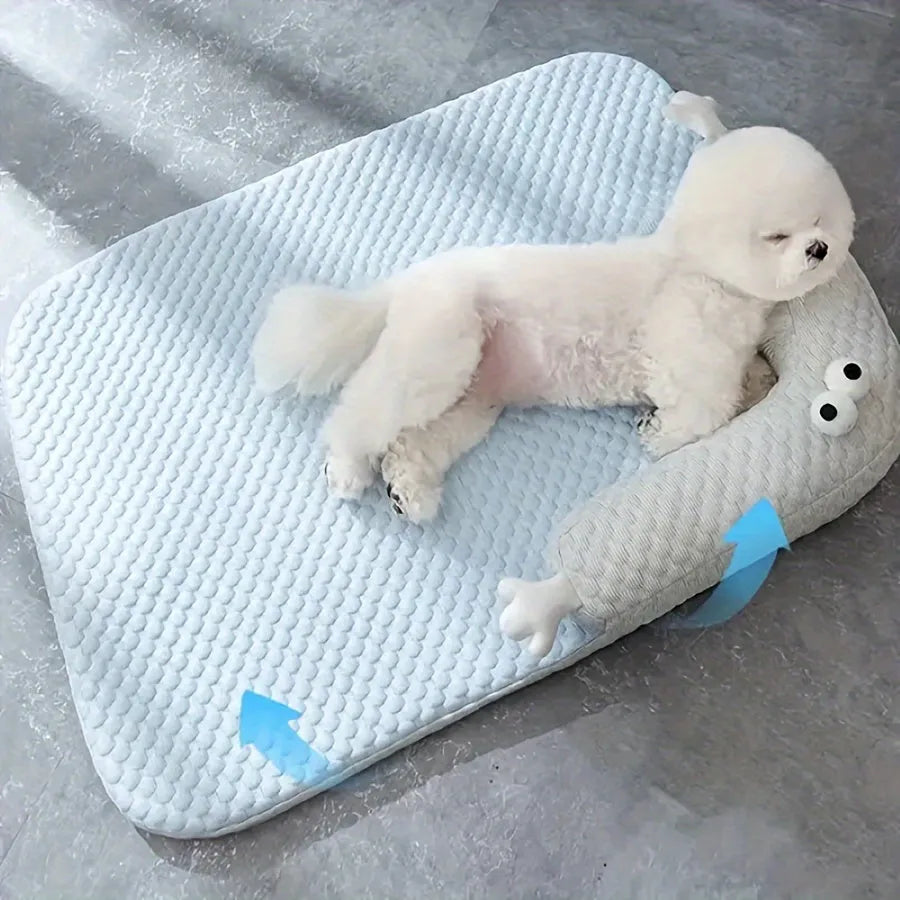 Blue pet bed cushion with big-eyed monster design on a wooden floor.