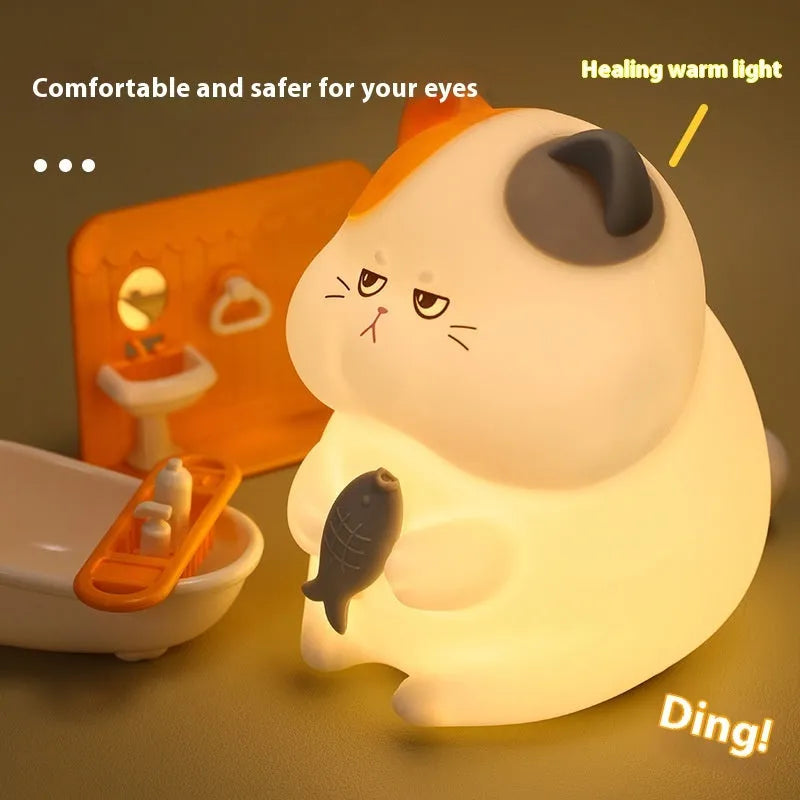 Small yellow Greedy Cat cartoon desktop night light with socket plug on desk.