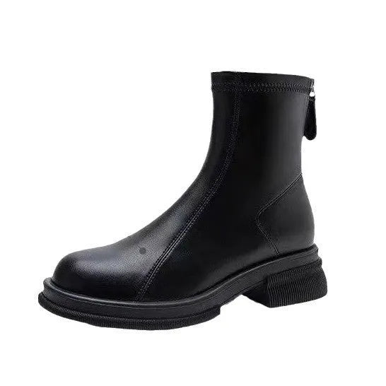 Women's black ankle boots with a thick flat heel, round toe, and rear zip fastener on a wooden floor.