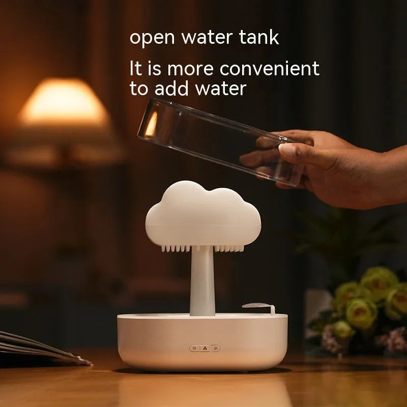 White cloud-shaped humidifier diffuser with multi-colour LED lights on a wooden surface.