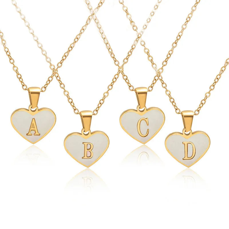 Gold-plated heart-shaped white shell initial necklace on a model, showing the adjustable clavicle chain.