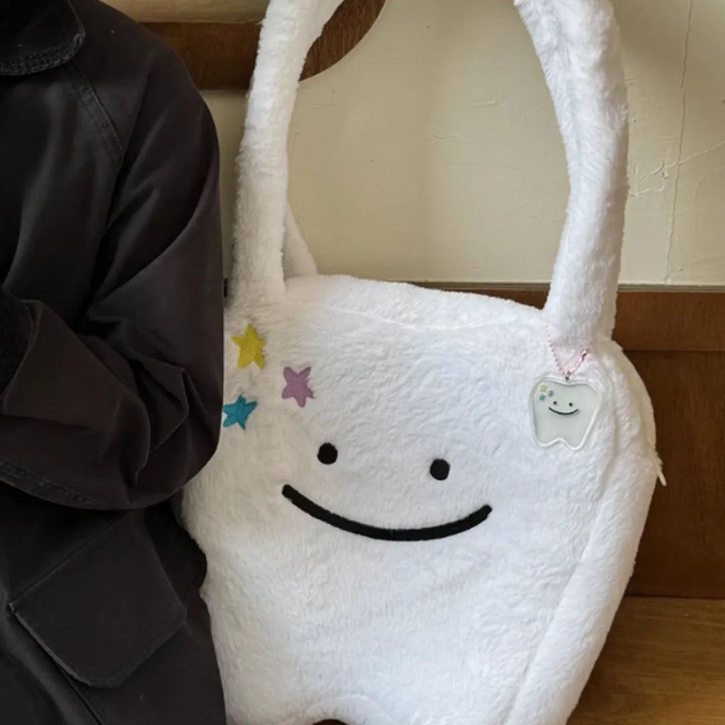 White plush tote bag with cute tooth graphic and a crossbody strap.