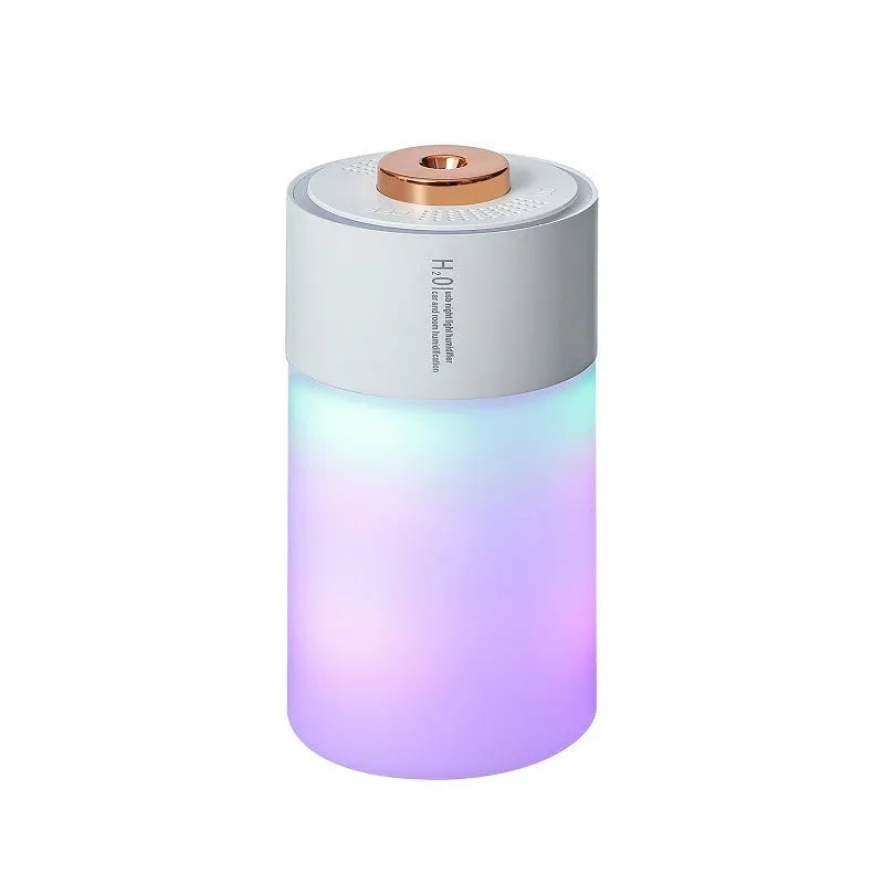 Pink column-shaped USB desk humidifier with colourful LED mist on a wooden surface.