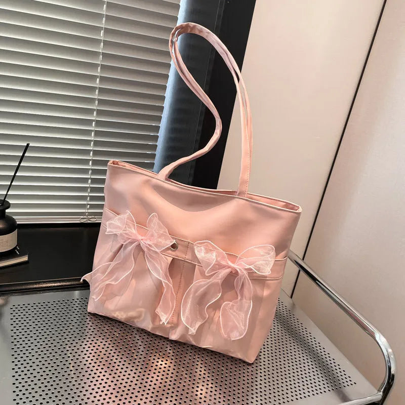 Black PU leather bow tote bag with double shoulder straps, shown with interior zipped pocket.