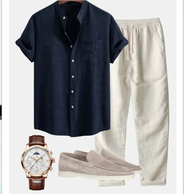 Man wearing a blue slim-fit stand collar short-sleeved shirt and trousers from a coordinated set with shoes and watch.