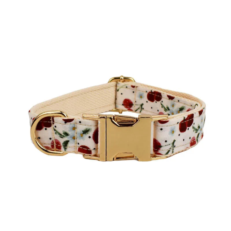 Red cherry printed cloth dog collar and leash set with matching vest, light gold buckle, and decorative bow strap.