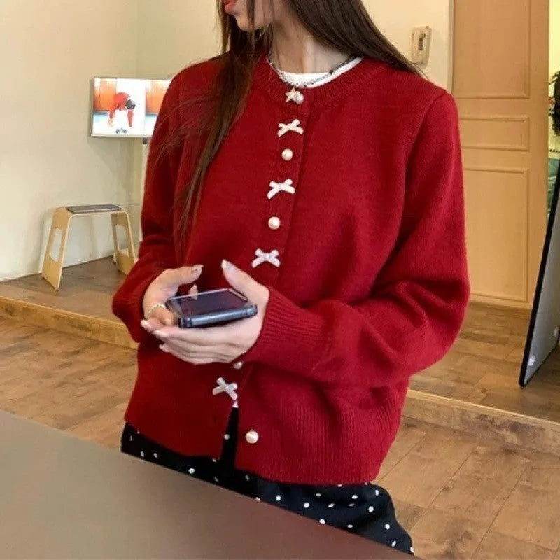 Women's solid colour cardigan with a front fabric bow and pearl button fastening, shown in a light colour.