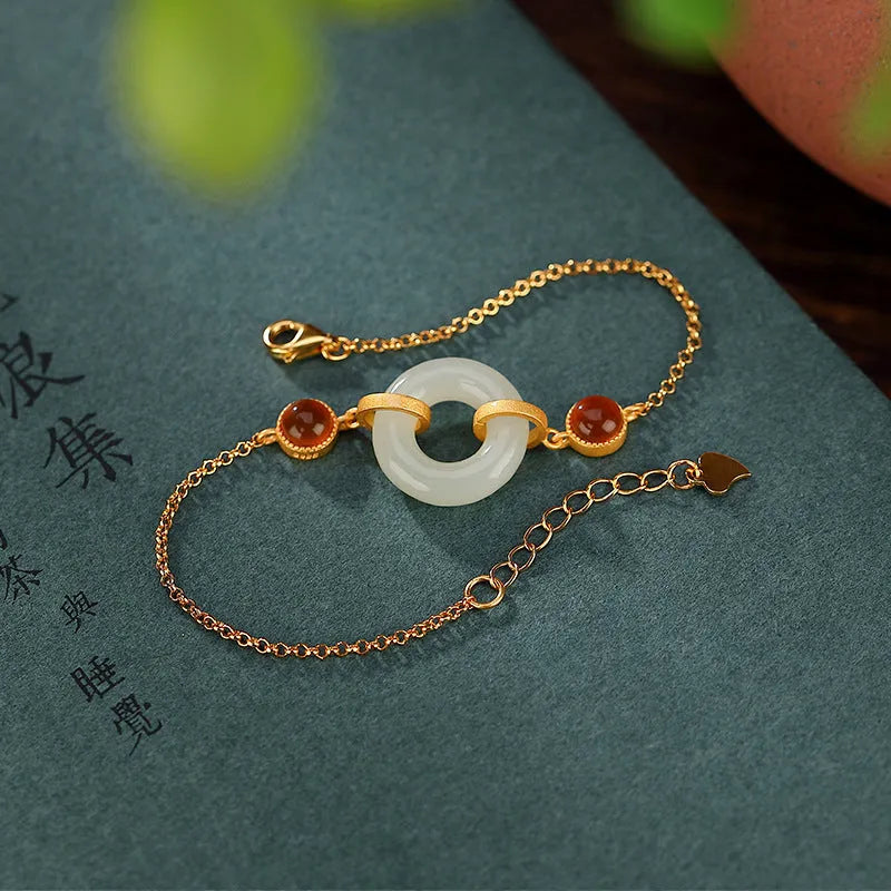 Gold-coloured women's bracelet with a silver base and an inlaid green Hetian jade charm, showing a peace buckle clasp.