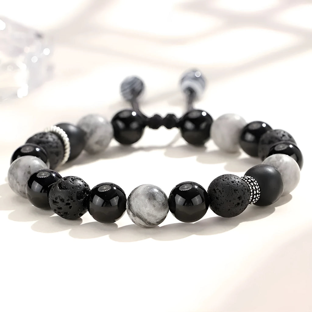 Black agate map stone volcanic rock bracelet with diamond-shaped beads on a wrist.