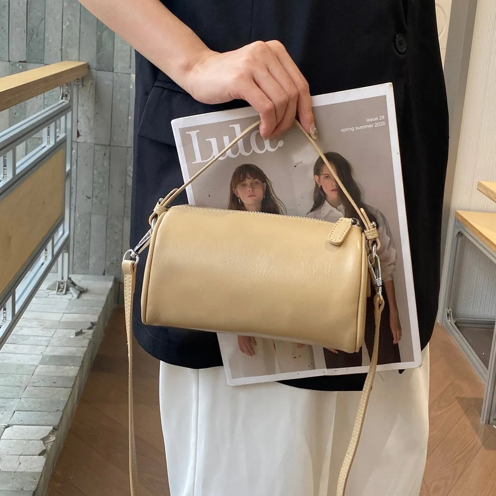 Cylindrical leather crossbody bag for mobile phones in six colours, showing visible sewing thread and compact size.