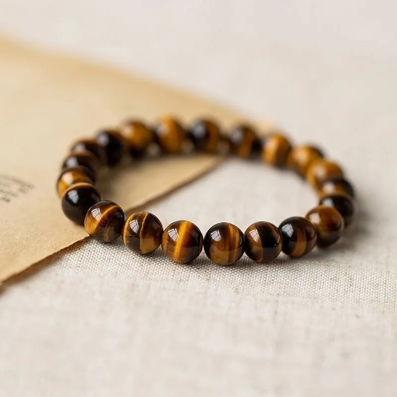 Close-up of a single circle tigereye stone Buddha rosary bracelet showing the chatoyant beads on a string.
