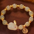 Green jade hare bracelet with black cord showing fu character charm and lily detailing