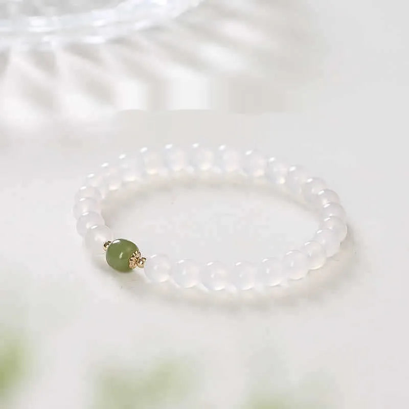 Handmade natural white agate and Hetian jade crystal bracelet with cinnabar inlay on a wrist.