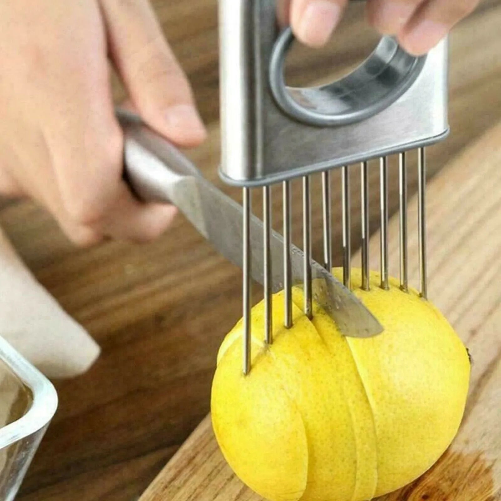 Stainless steel onion holder slicer with sharp prongs and a red finger guard on a kitchen counter.