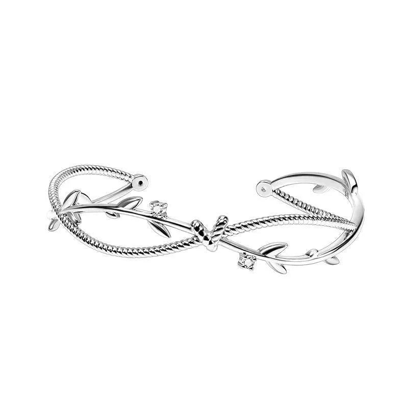 Close-up of an adjustable white gold coloured copper bracelet with a twisted branch and sprout design.
