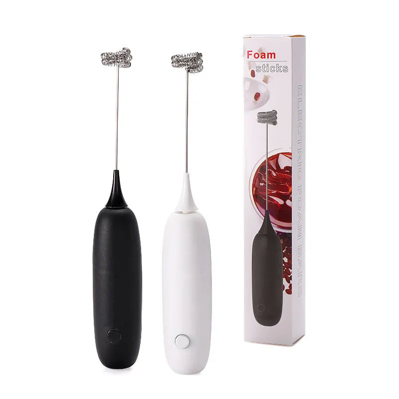 Hand-held milk frother with stainless steel whisk in modern black design creating microfoam in coffee cup