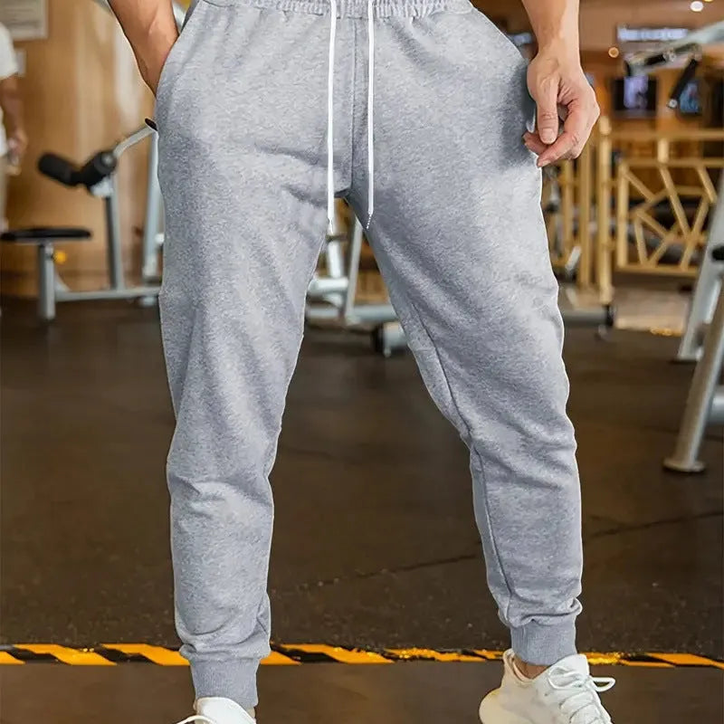 Men's beige loose-fit leisure trousers with an elastic drawstring waist and a thin 3D pattern fabric.