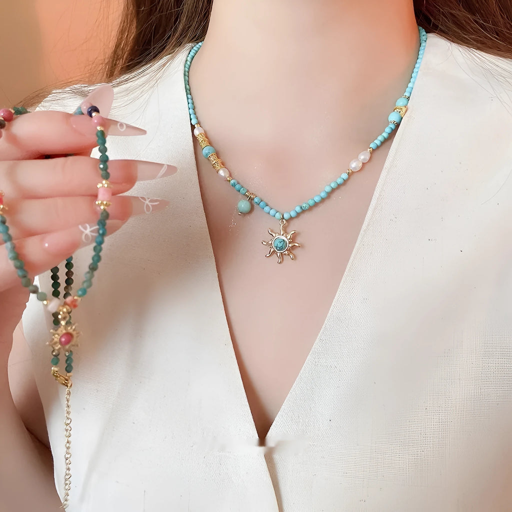 Freshwater pearl necklace with a blue stone sun pendant on a delicate clavicle chain.