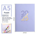 2025 A5 schedule book with faux leather cover in blue, showing open pages on a desk