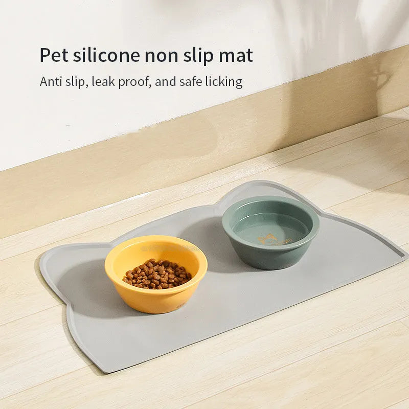 Blue cat head shaped silicone pet feeding mat placed under food and water bowls.