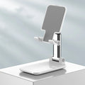 White telescopic folding mobile phone bracket on desktop holding smartphone