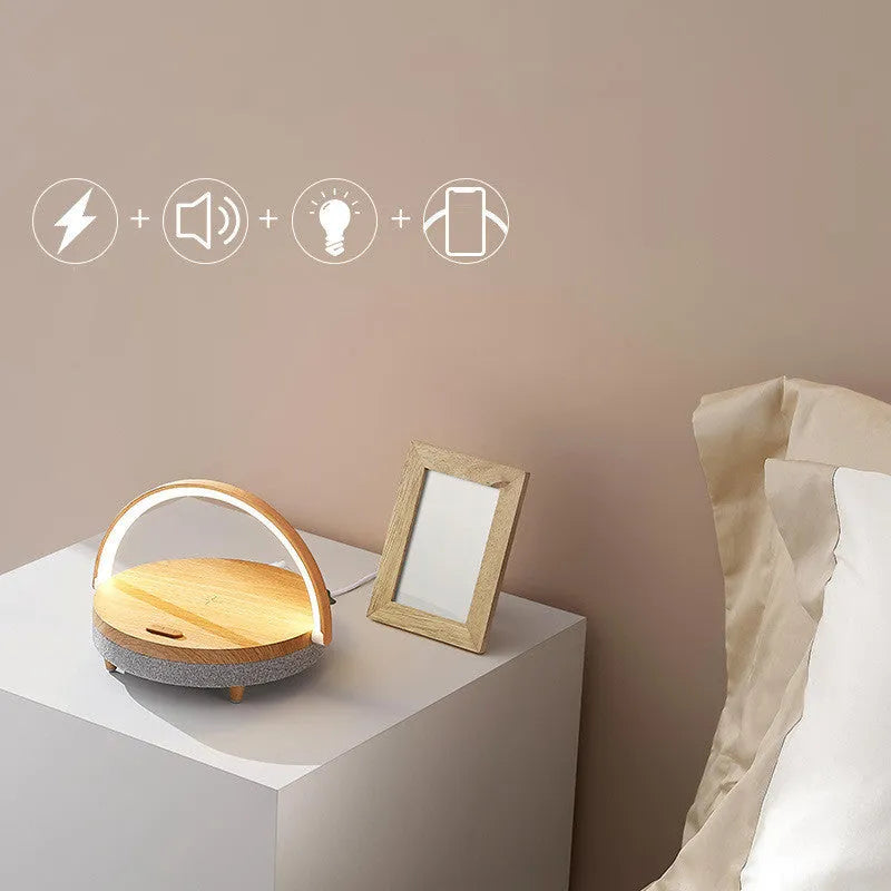 White marble-pattern wireless charging LED night light with built-in Bluetooth speaker and phone holder on wooden table.