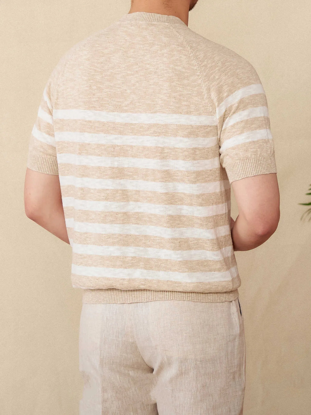 Man wearing a navy blue and white striped short sleeve linen-cotton blend t-shirt with a round neck.