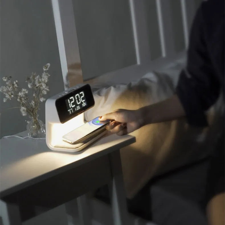 White bedside lamp with integrated wireless charging pad, LCD alarm clock screen, and touch-sensitive dimming controls.