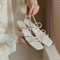 Women's flat strap gladiator sandals with square toe and adjustable ankle ties in beige.