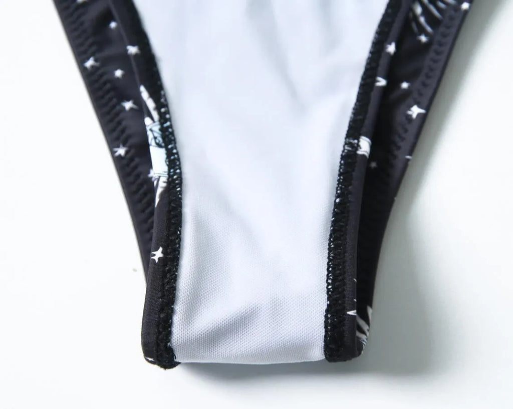 Black printed one-piece swimsuit with a split tube top and backless design.